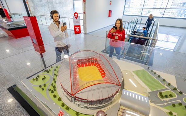 Benfica stadium scale model with visitors taking photos in the exhibit room.