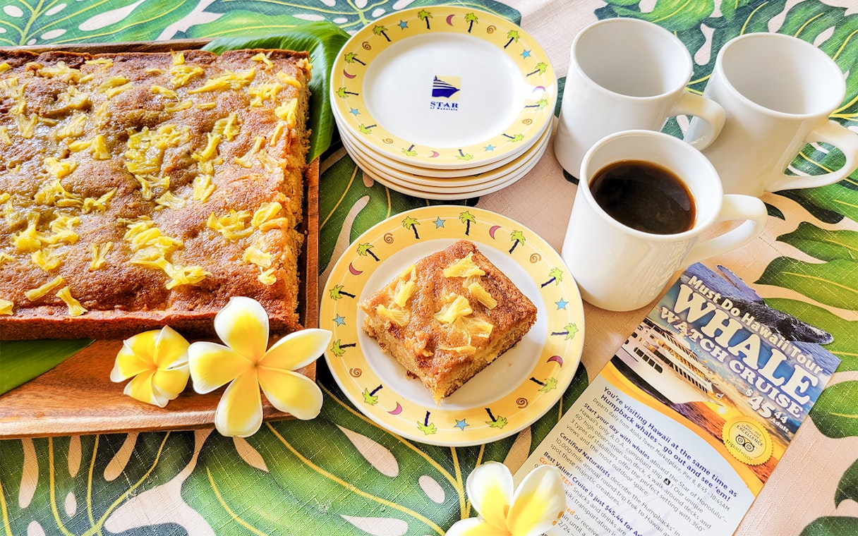 Whale watching cruise in Oahu with pineapple cake and coffee served on a tropical-themed table.