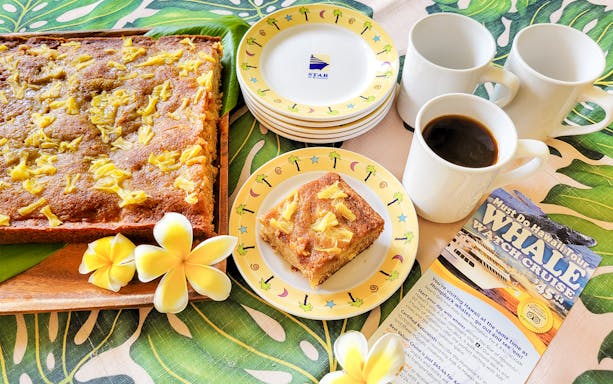 Whale watching cruise in Oahu with pineapple cake and coffee served on a tropical-themed table.