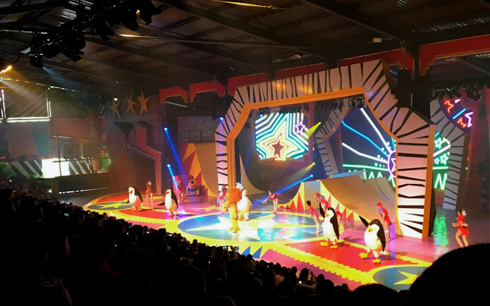 Madagascar-themed circus show with performers and penguin costumes at Beto Carrero.