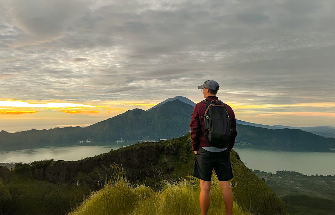 Hiker overlooking Mount Batur at sunrise in Bali, Indonesia.