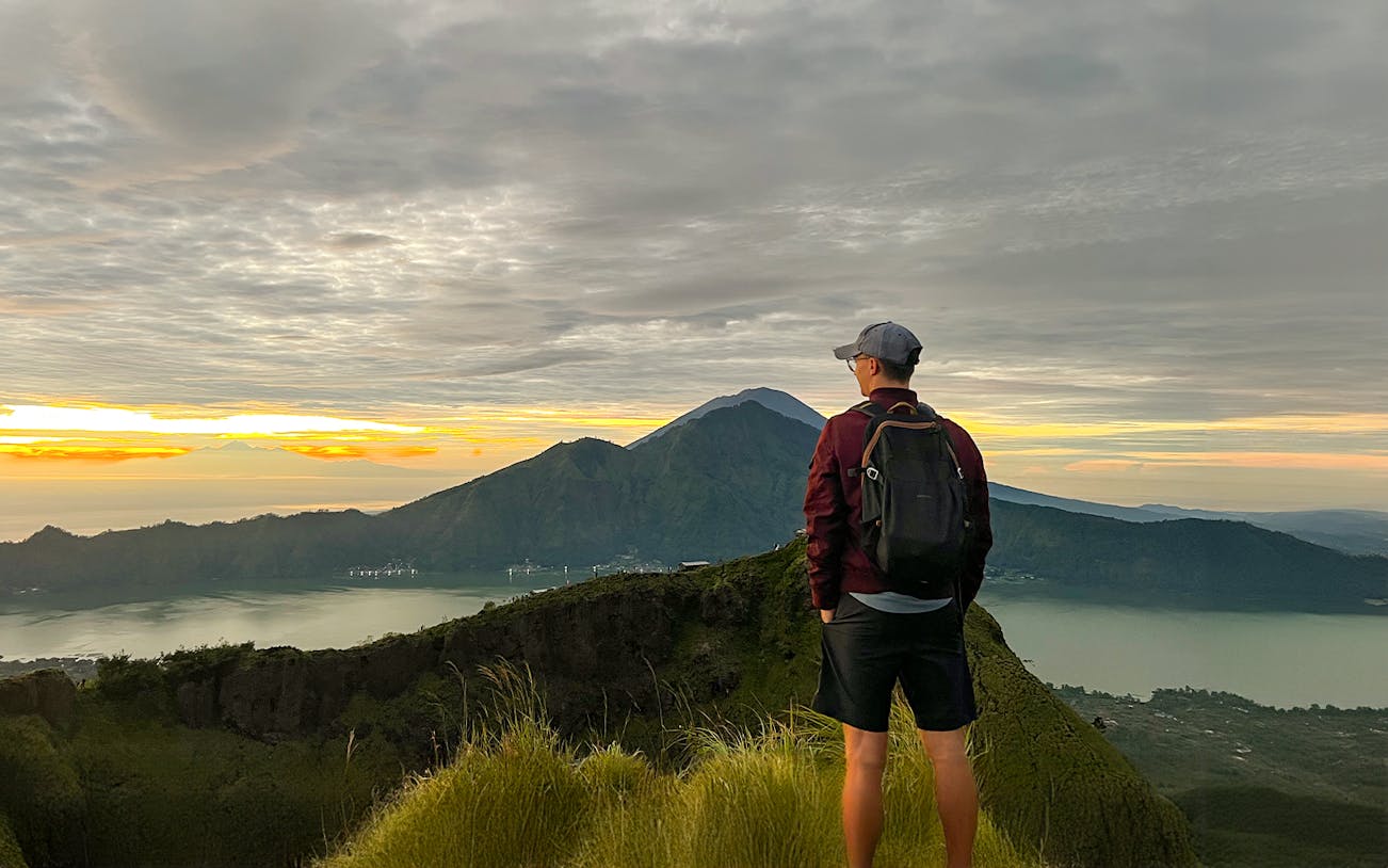 Hiker overlooking Mount Batur at sunrise in Bali, Indonesia.