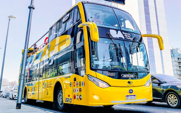 Yellow double-decker Buenos Aires tour bus on city street.