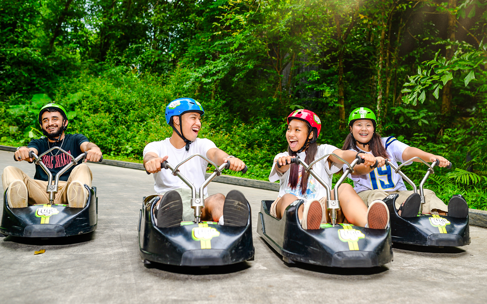 Family enjoying Skyline Luge ride in Singapore amidst lush greenery.