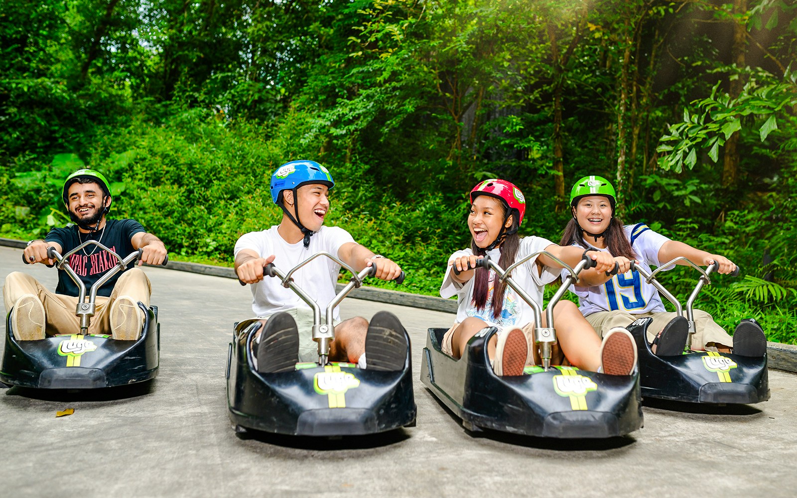 Family enjoying Skyline Luge ride in Singapore amidst lush greenery.