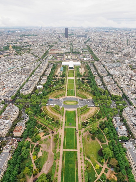 Aerial view of Paris from the Eiffel Tower, showcasing the Champ de Mars and cityscape.