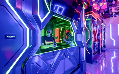 Visitors engaging in a VR game at Pixoul Gaming with neon-lit futuristic booths.