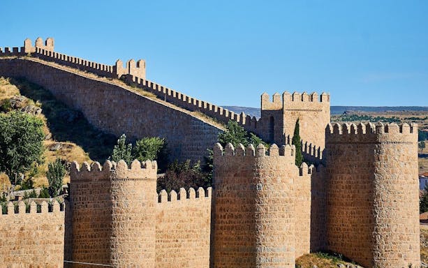 Walls of Ávila with crenellated towers and stone fortifications in Spain.