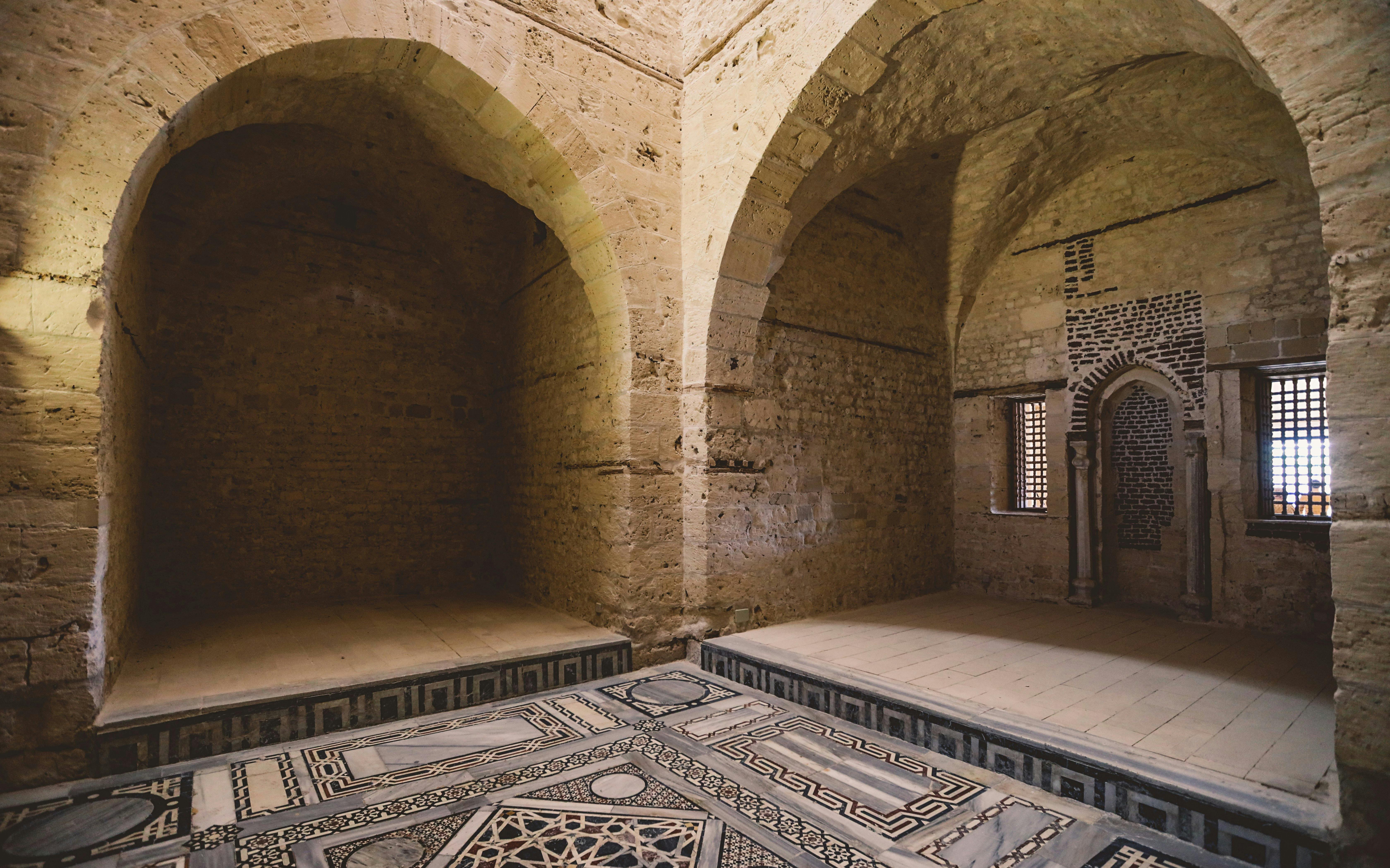 Interior of the mosque inside the Citadel of Qaitbay, Egypt, featuring stone arches and intricate floor patterns.