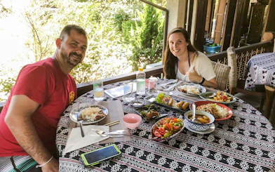 Dining experience at Chiang Mai Elephant Sanctuary with traditional Thai dishes on a patterned table.