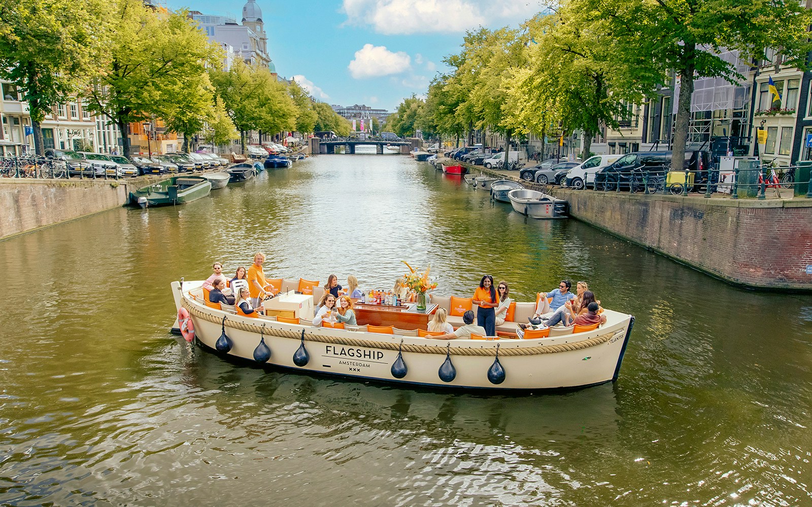 Luxury open boat cruising through Amsterdam's canals with historic buildings in the background.