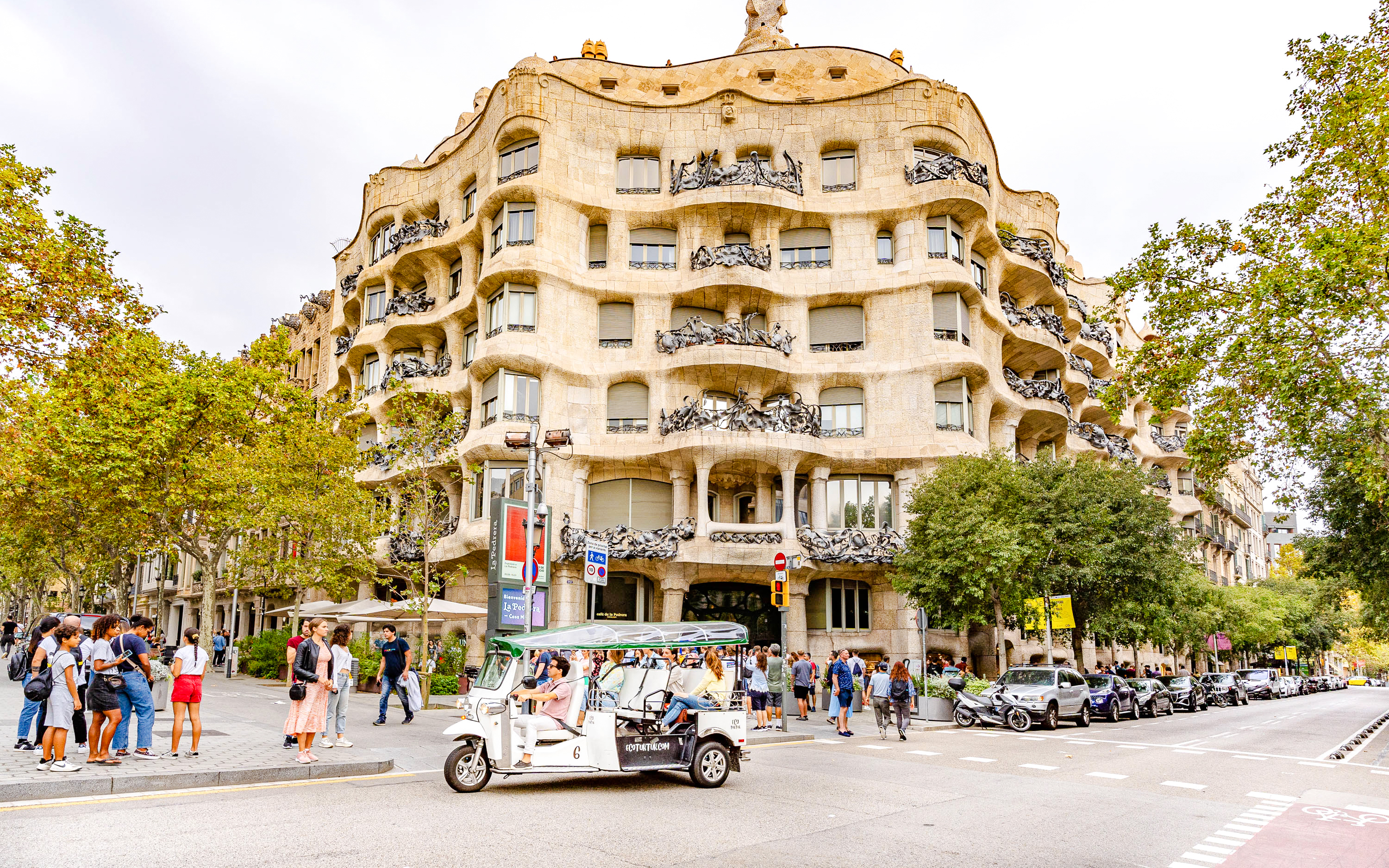 Tuk tuk driving past La Pedrera (Casa Mila) in Barcelona.