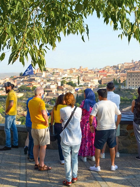 Tourists with a guide overlooking Toledo from Mirador del Valle viewpoint.