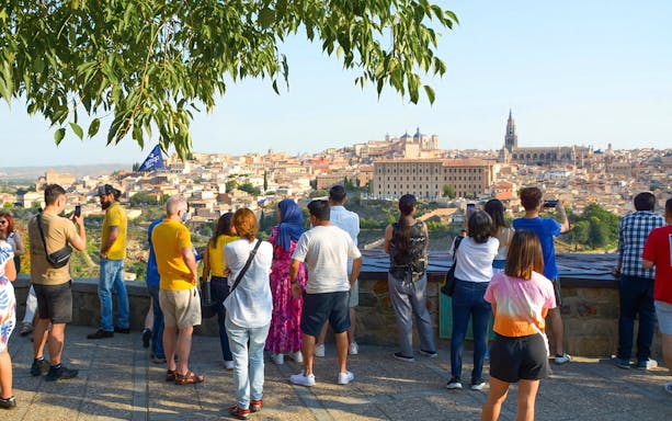 Tourists with a guide overlooking Toledo from Mirador del Valle viewpoint.