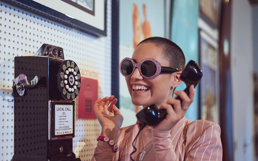 Person using vintage phone at Pink Palace exhibit.