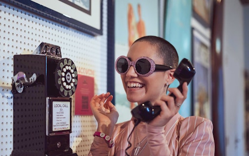 Person using vintage phone at Pink Palace exhibit.