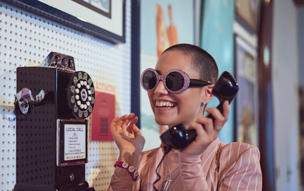 Person using vintage phone at Pink Palace exhibit.