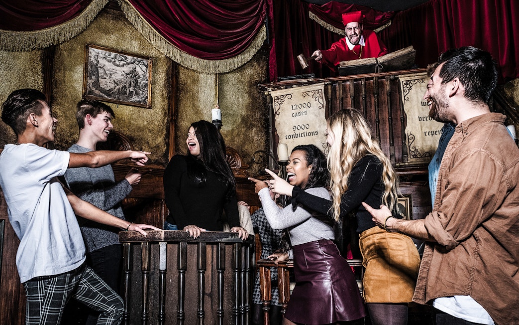 Guests interacting with a performer at the Amsterdam Dungeon courtroom scene.