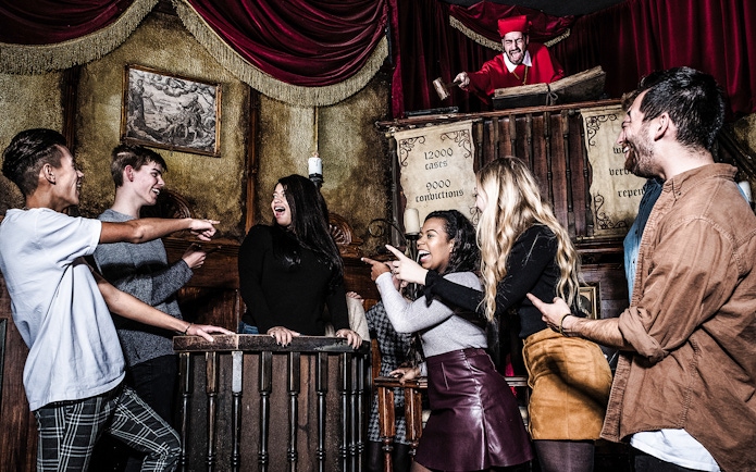 Guests interacting with a performer at the Amsterdam Dungeon courtroom scene.