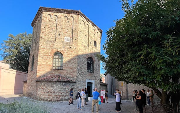 Tour group outside a historic brick building in Ravenna, Italy, during a UNESCO monuments guided tour.
