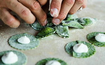 Hands shaping green pasta during a cooking class at an agritourism in Bardolino, Lake Garda.