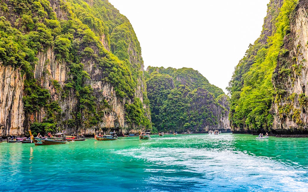 Longtail boats in turquoise waters of Pileh Lagoon, surrounded by limestone cliffs, Krabi.