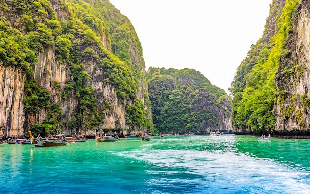 Longtail boats in turquoise waters of Pileh Lagoon, surrounded by limestone cliffs, Krabi.