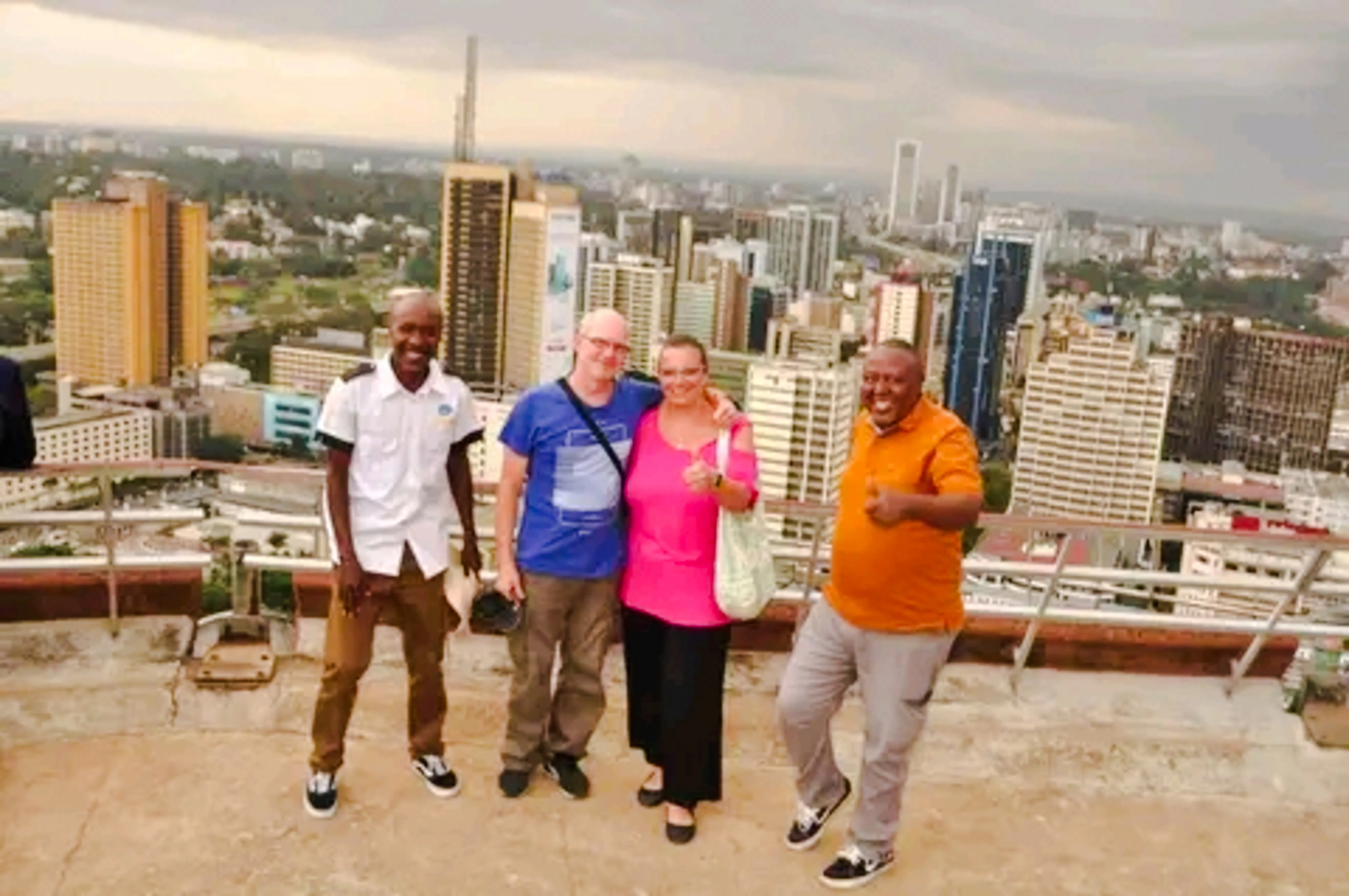 Group of tourists on a rooftop with Nairobi skyline during city orientation tour.
