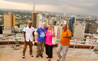 Group of tourists on a rooftop with Nairobi skyline during city orientation tour.