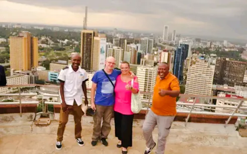 Group of tourists on a rooftop with Nairobi skyline during city orientation tour.