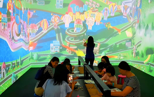 Visitors engaging in interactive activities at Wonderpark Melaka with colorful digital displays.