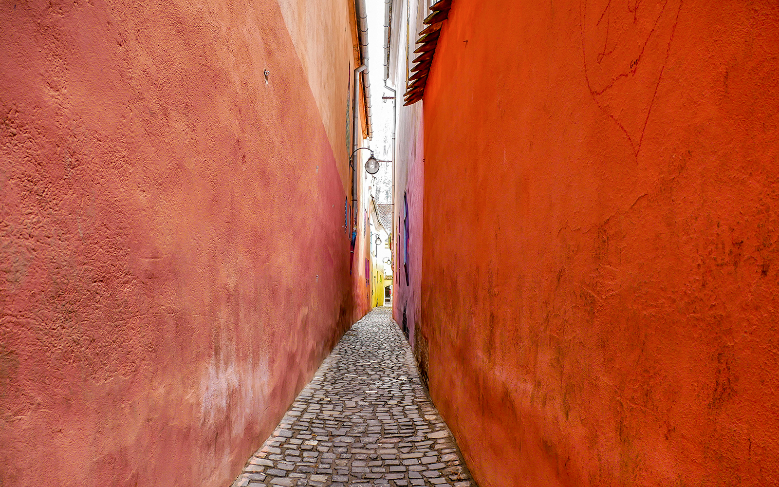 Narrow cobblestone alley of Rope Street, Brasov with colorful walls.