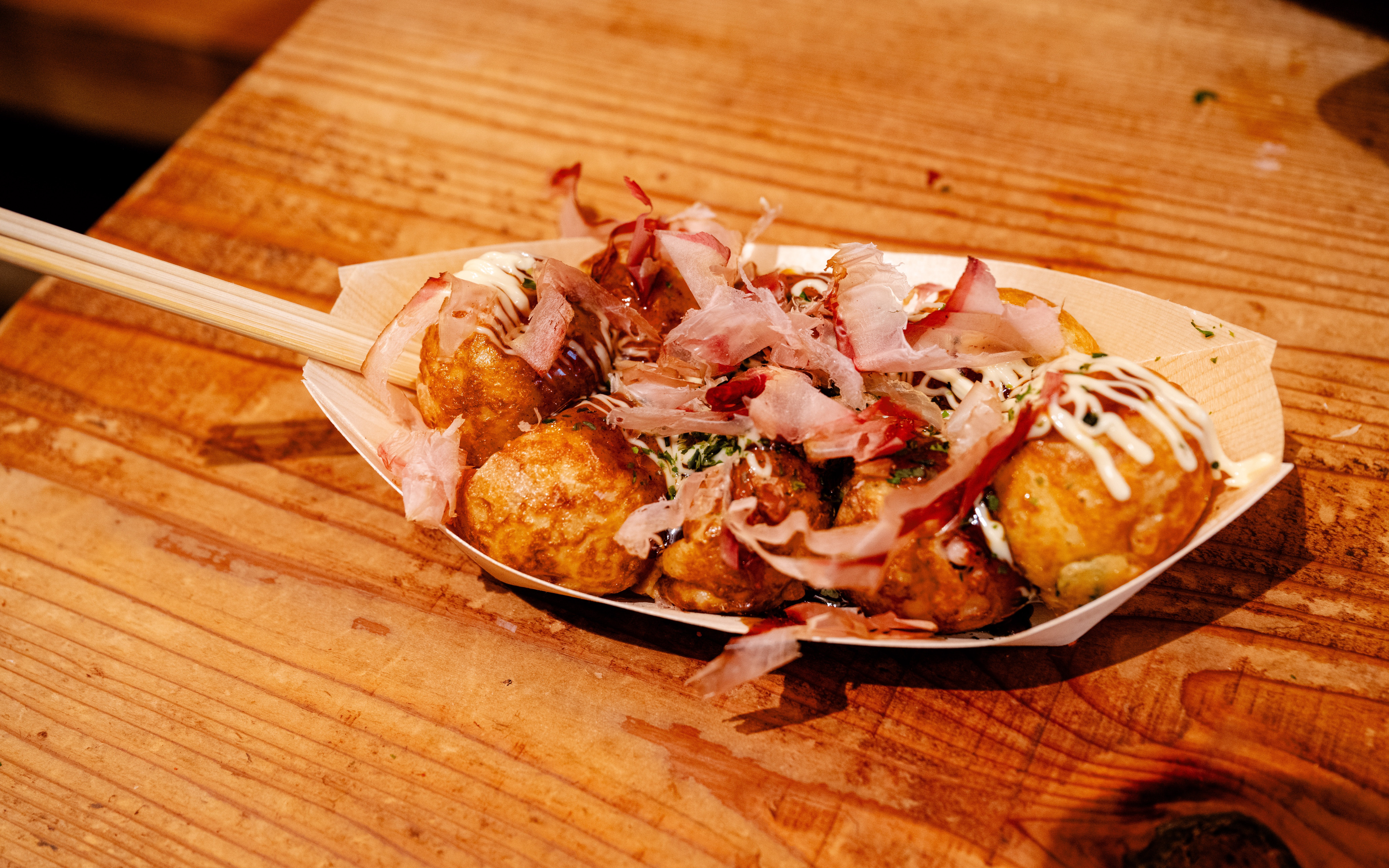 Takoyaki octopus balls with bonito flakes on a wooden plate.