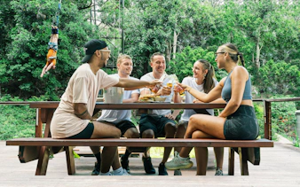 Visitors enjoying lunch at a picnic table in Skypark Cairns with a bungee jumper in the background.