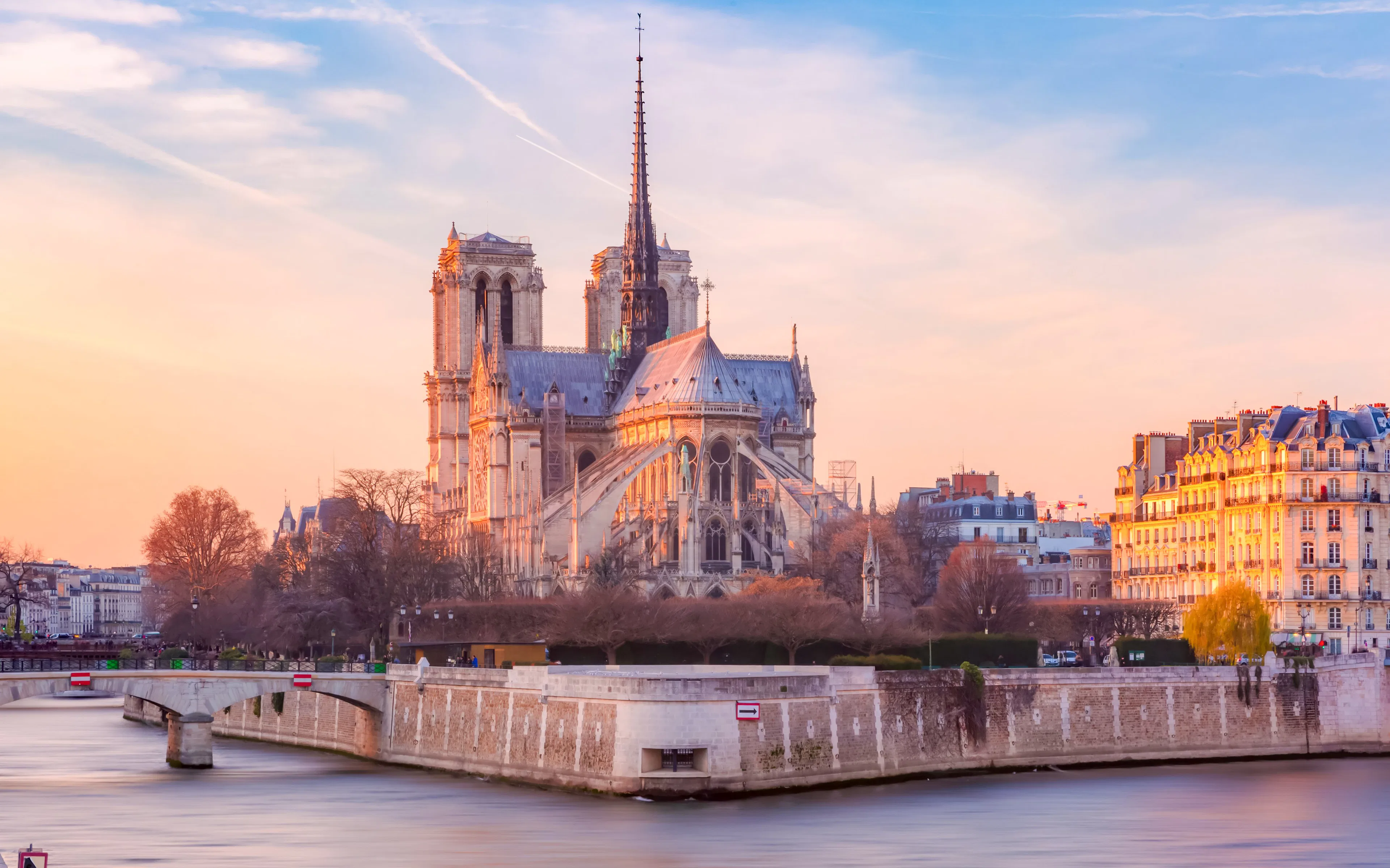 Cathedral of Notre Dame de Paris at sunset with Seine River in foreground, France.