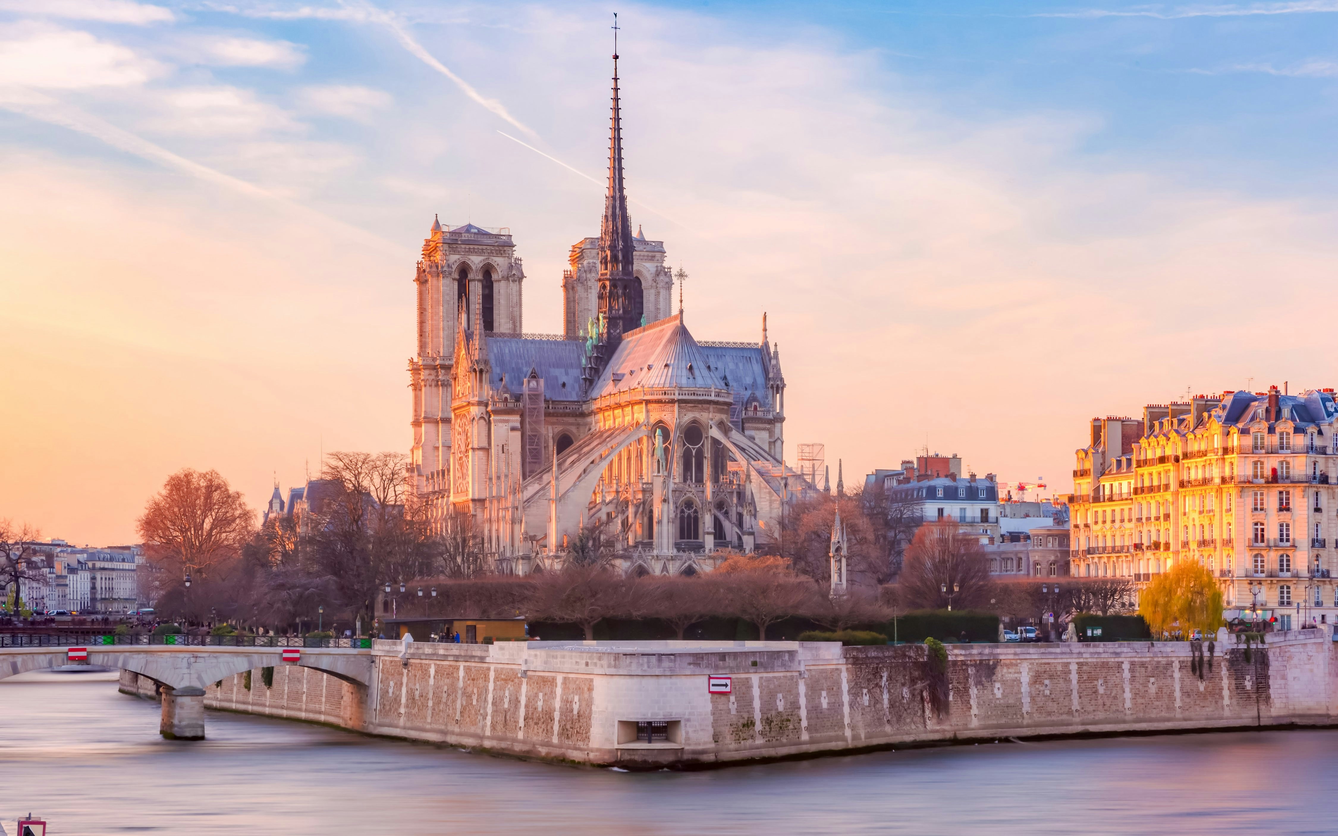 Cathedral of Notre Dame de Paris at sunset with Seine River in foreground, France.