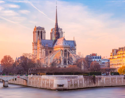 Cathedral of Notre Dame de Paris at sunset with Seine River in foreground, France.