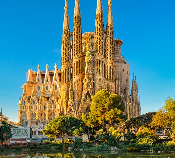 Sagrada Familia in Barcelona, Spain, reflected in a pond during golden hour.