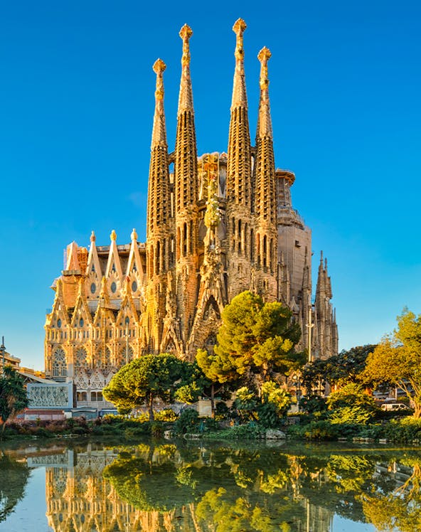 Sagrada Familia in Barcelona, Spain, reflected in a pond during golden hour.