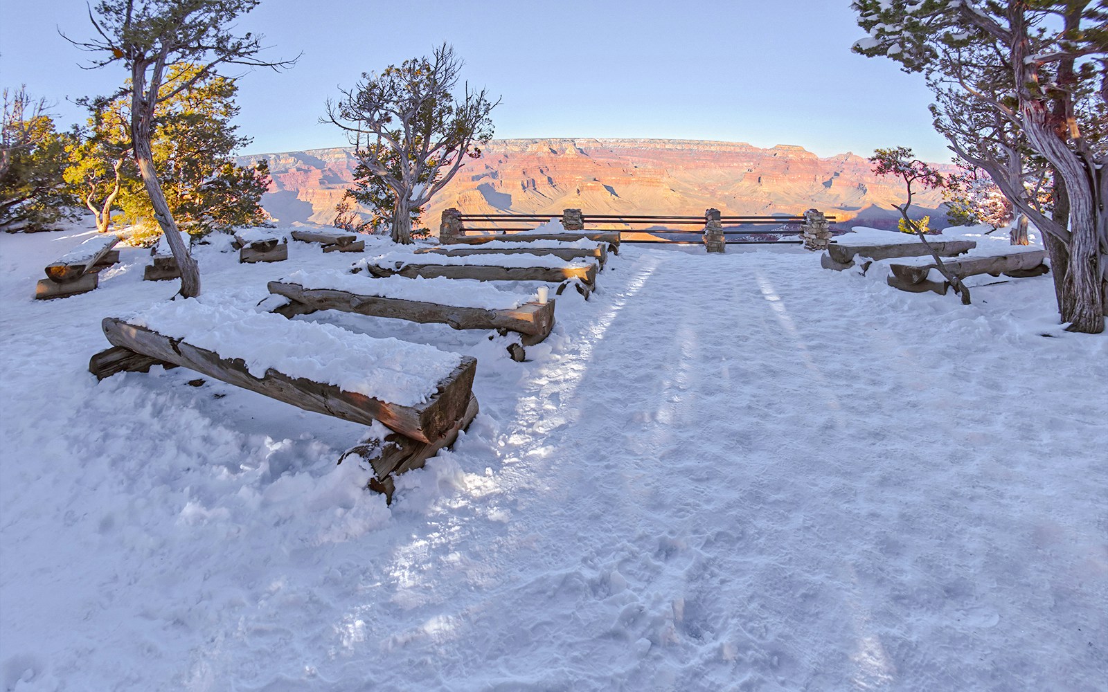 Snow-covered benches at Yavapai Point Amphitheater, Grand Canyon, with canyon view.