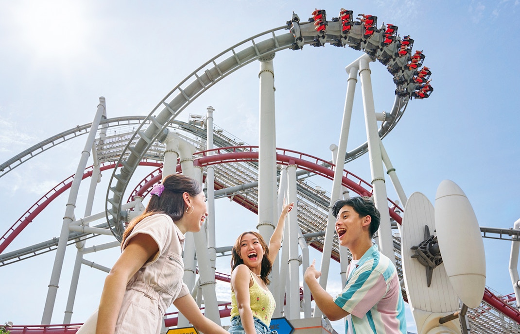 Family posing near roller coaster at Universal Studios Singapore.