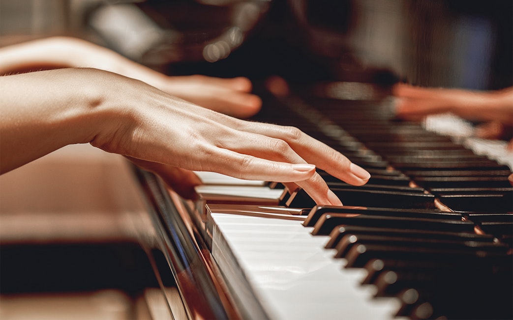 Hands playing piano keys in a close-up view.