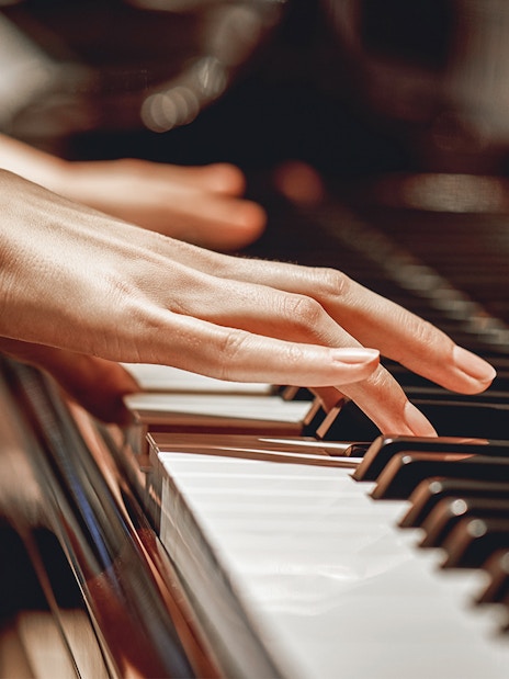 Hands playing piano keys in a close-up view.