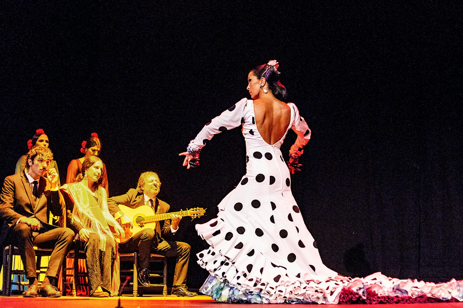 Flamenco dancer performing on stage with musicians during Emociones show.