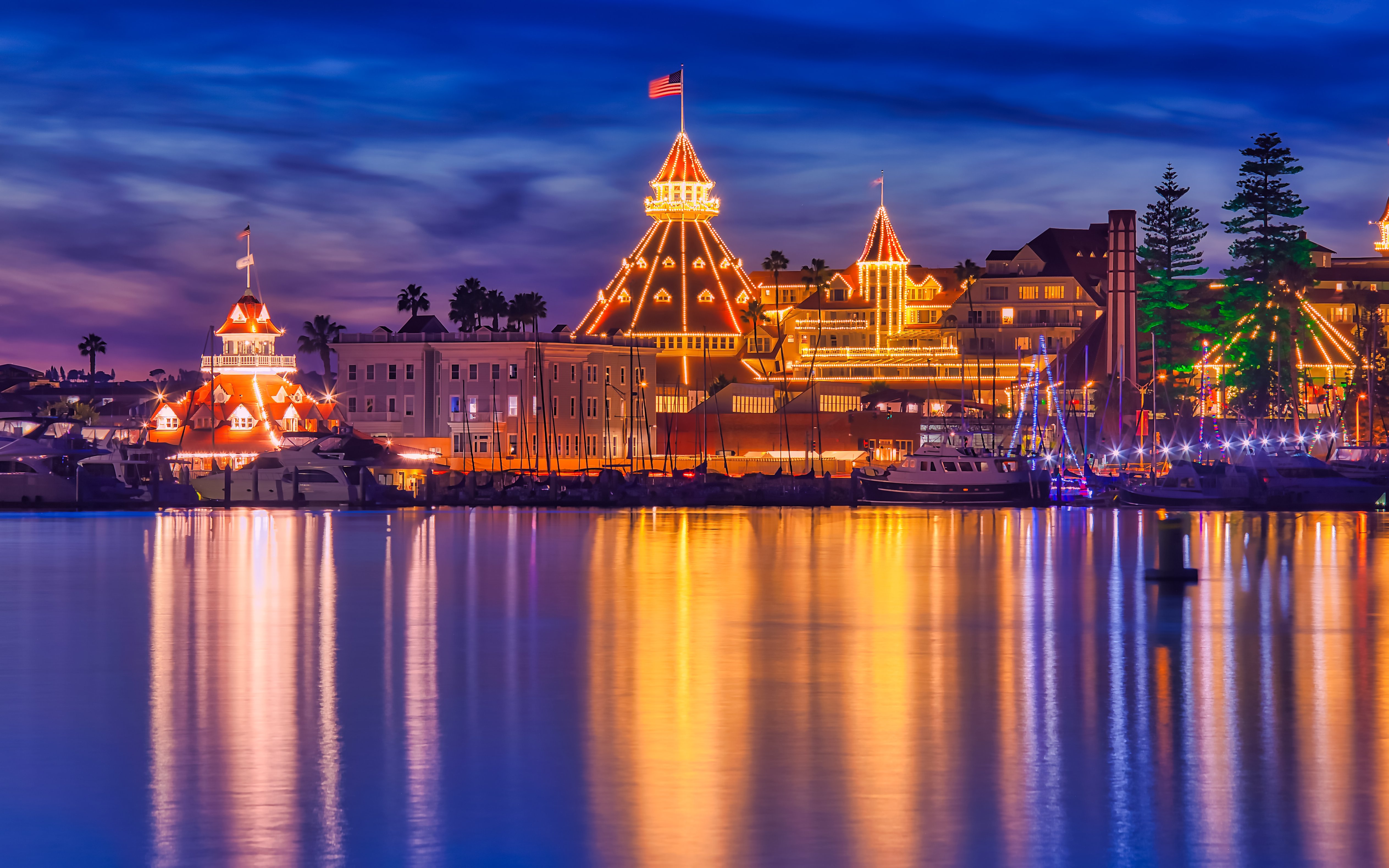 San Diego Bay Parade of Lights with illuminated buildings reflecting on the water.
