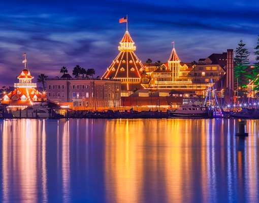 San Diego Bay Parade of Lights with illuminated buildings reflecting on the water.