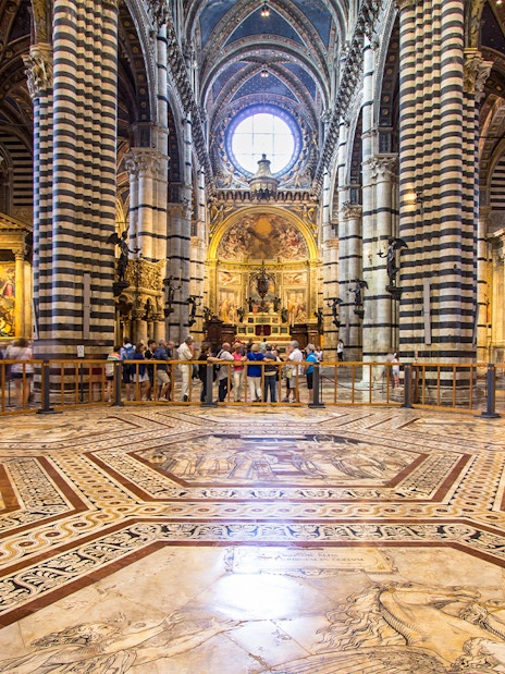 Siena Cathedral interior with striped columns and ornate marble floor, Italy.