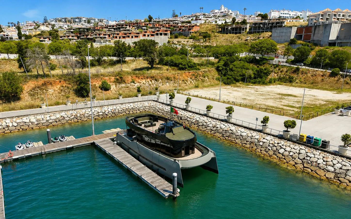 Espirito Oceanico boat docked in a marina with hillside town in the background.