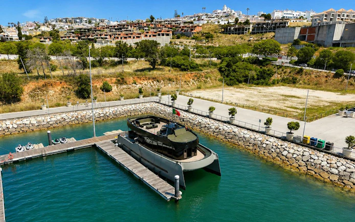 Espirito Oceanico boat docked in a marina with hillside town in the background.