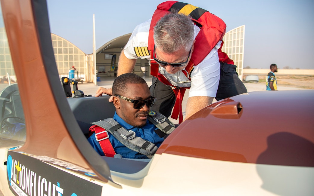 Pilot assisting passenger in cockpit for GFORCE Aerobatic Passenger Experience.